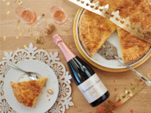 A bottle of Domaine Divio Crémant Rosé on a table with a slice of Galette.