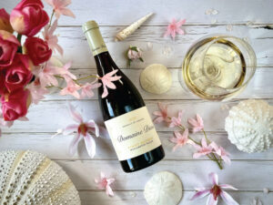 A bottle of Domaine Divio Pinot Beurot on a table with flowers and sea shells.